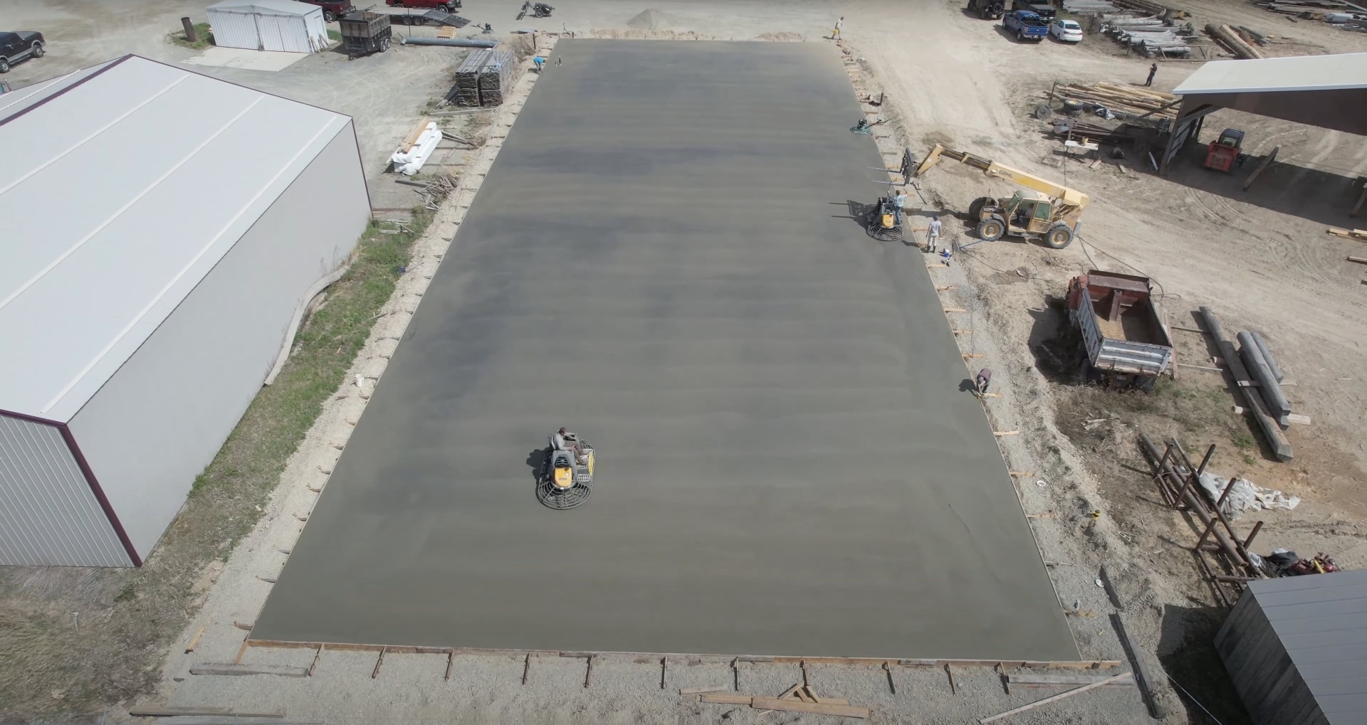 Large commercial concrete slab installation with heavy equipment and professional crew
