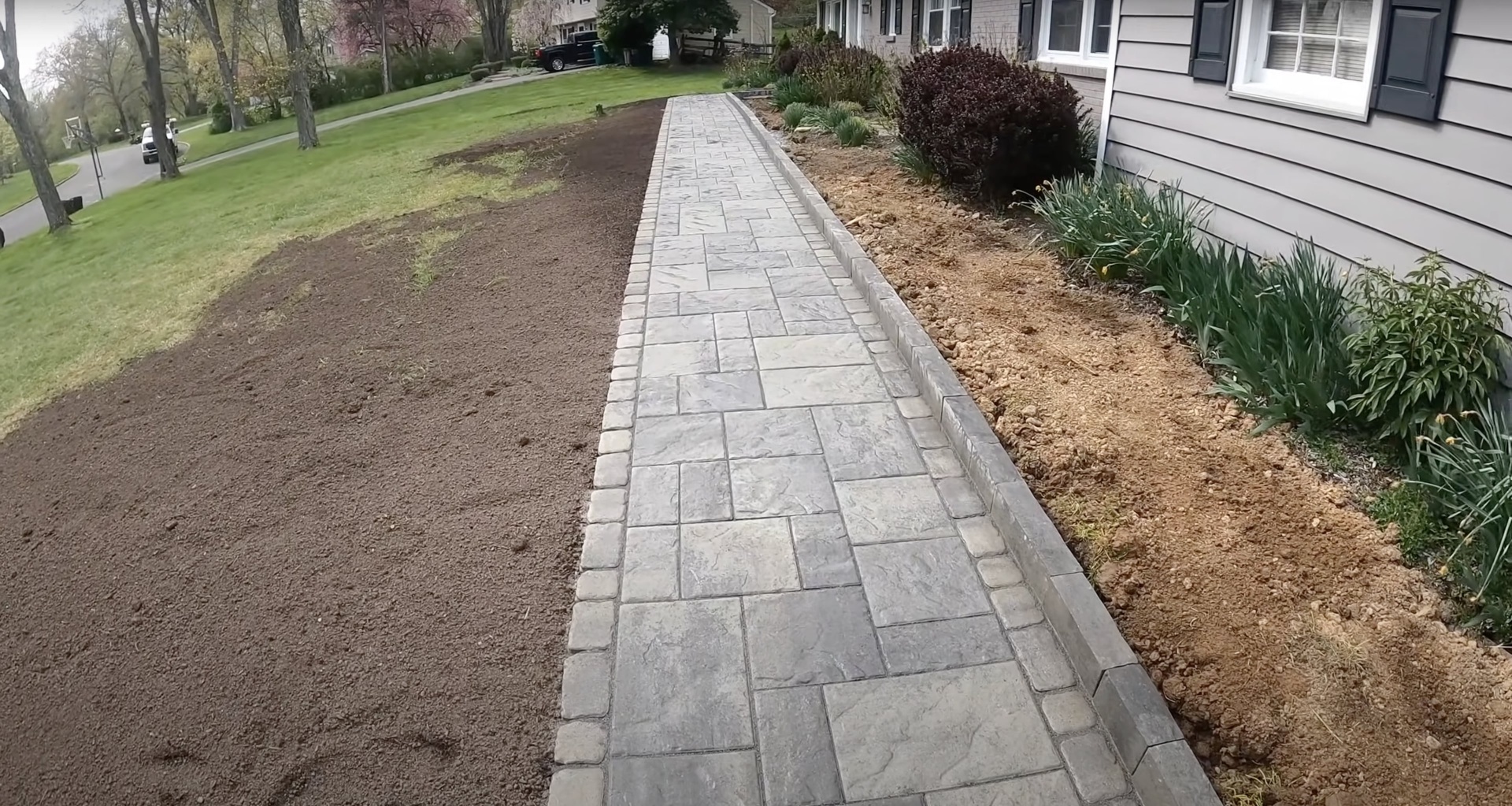 Stamped concrete walkway installation with decorative border and landscaping integration