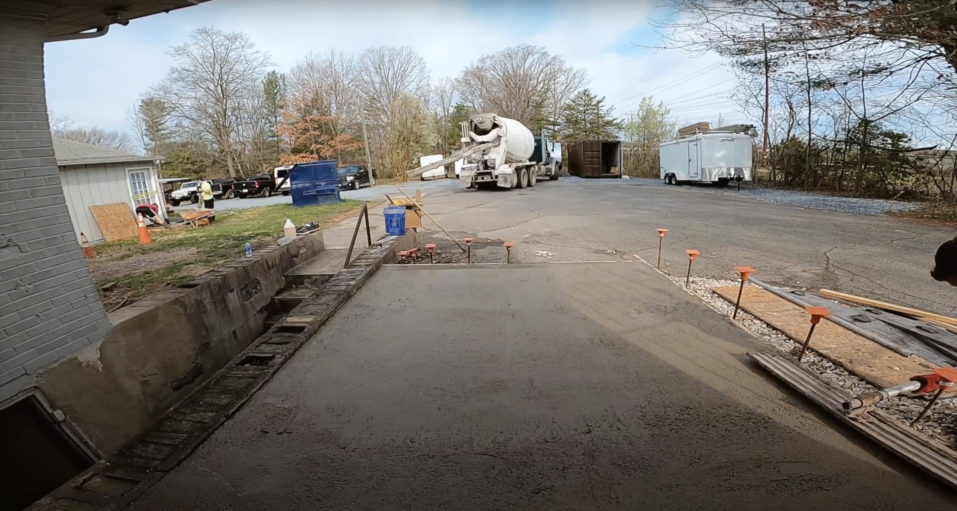 Professional concrete driveway installation in progress with concrete mixer truck and construction equipment